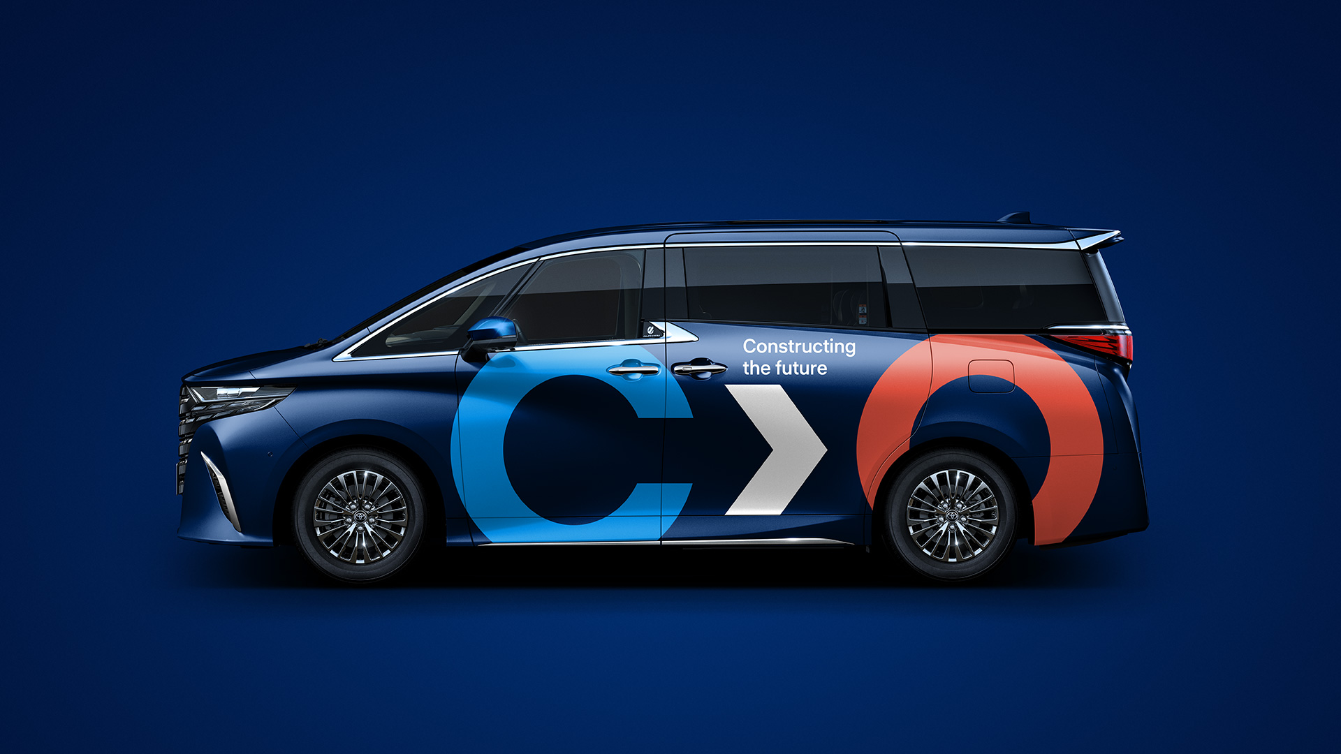 Side view of a navy Toyota Alphard with Constructor Group vehicle branding: a cyan C, white arrow, coral O and Constructing the future tagline