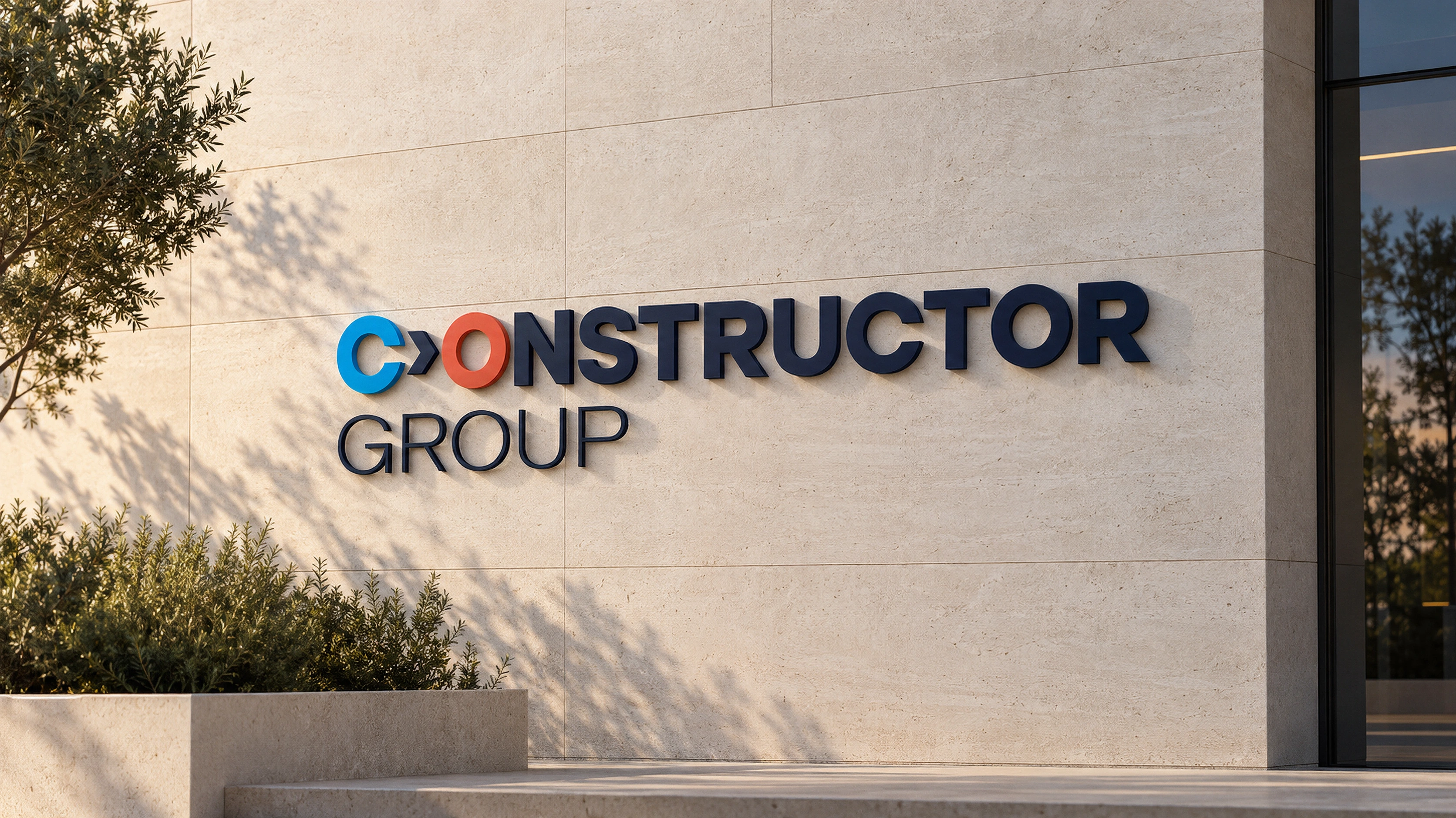 Constructor Group dimensional signage on a sunlit pale stone facade — refreshed brand mockup
