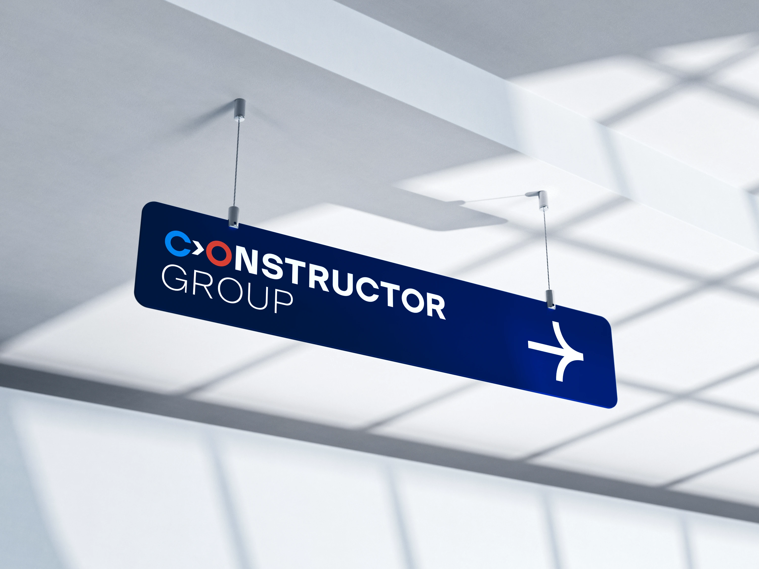 Constructor Group suspended wayfinding sign in navy with white directional arrow