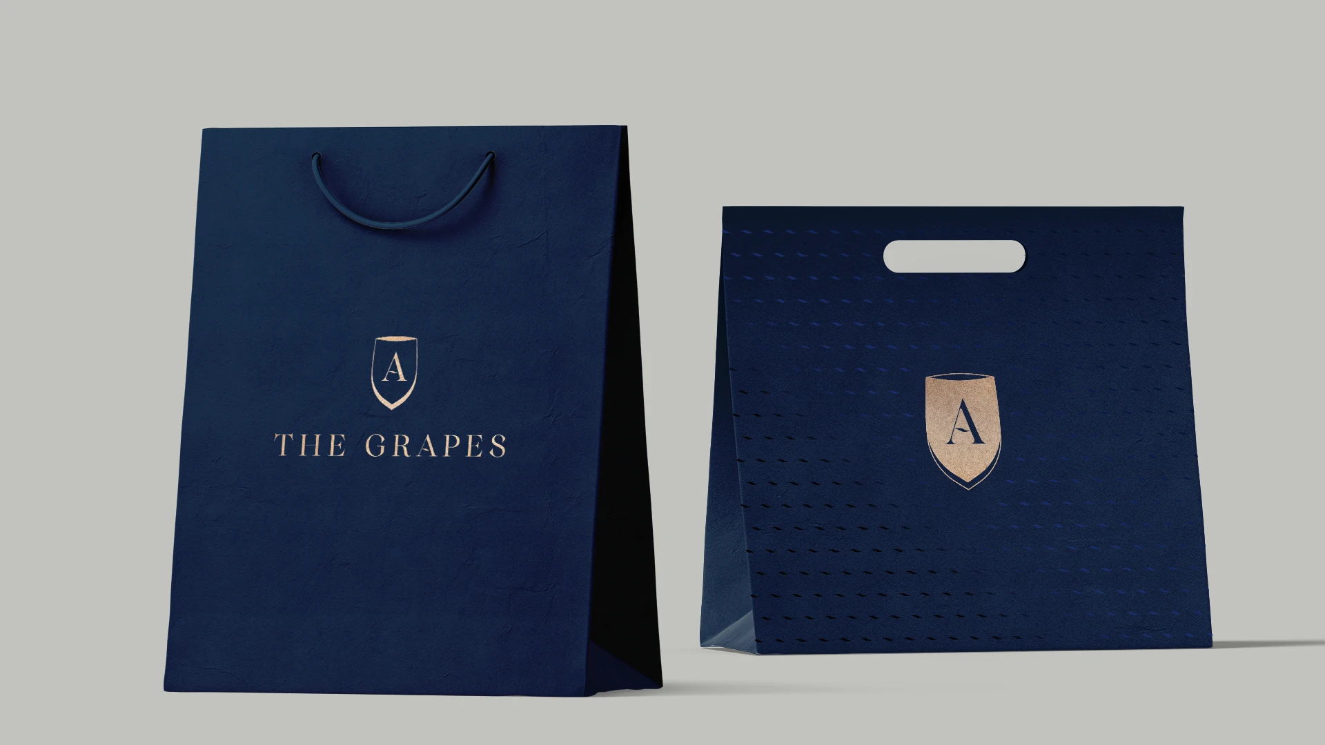 The Grapes navy retail bags with gold wordmark and shield